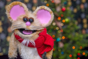 Buttons the Christmas Mouse standing in front of his sparkling Christmas tree