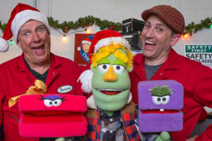 Chip, Bernie, Kent Cook, Carl, and Mel pose together in the North Pole workshop during a festive Christmas puppet adventure.